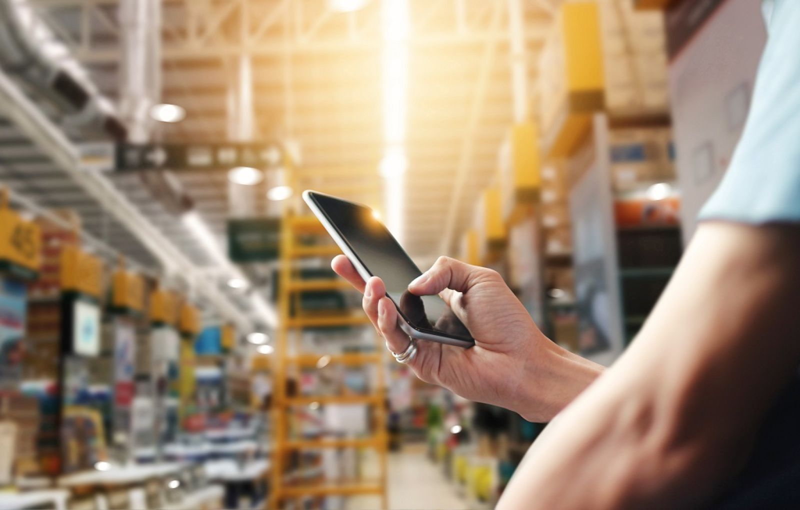 Person mit Smartphone in der Hand in einem Lager